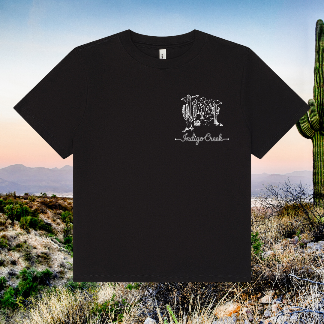 Black t-shirt with a white graphic design on a desert landscape background