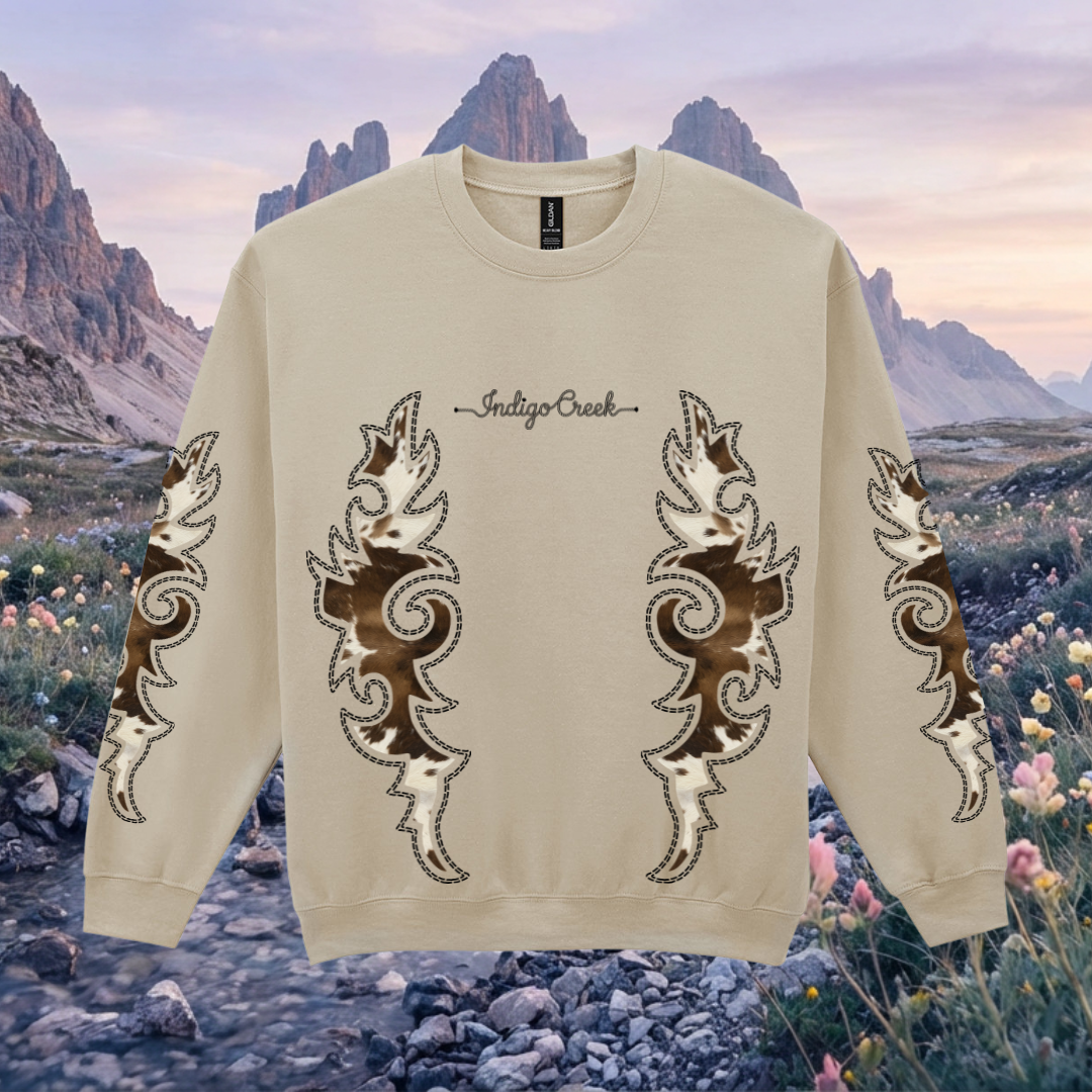Beige sweatshirt with decorative boot stitch patterns on a scenic western background of mountains and flowers.