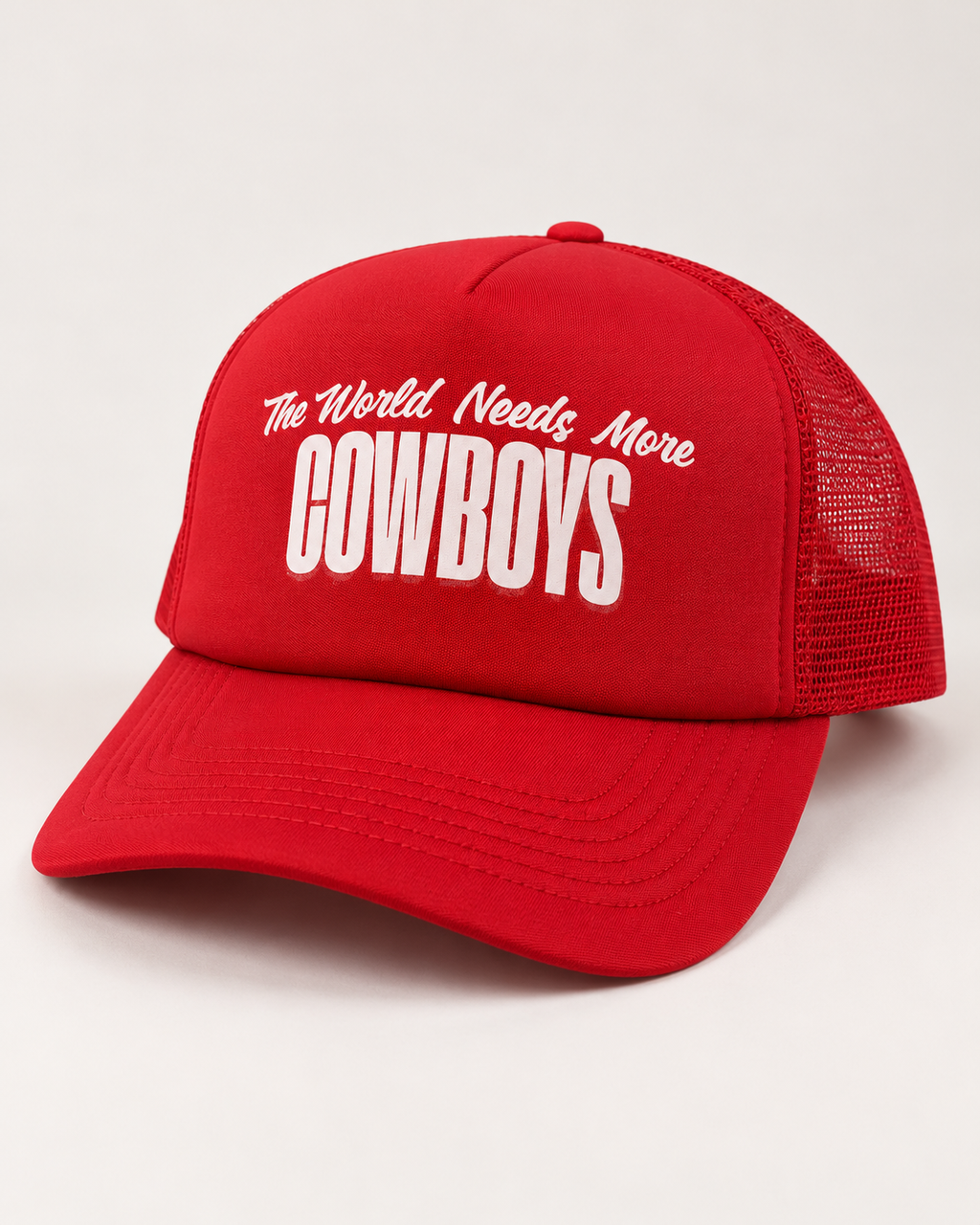A red trucker-style baseball cap with white embroidered text reading 'The World Needs More COWBOYS' on the front panel, shown against a plain light background.