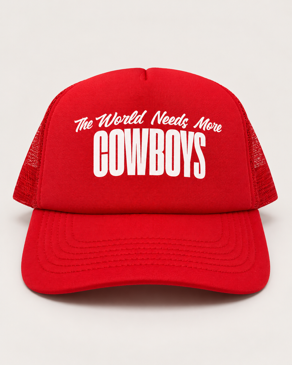 A red trucker hat with white text reading 'The World Needs More COWBOYS' on the front, shown against a light gray background.