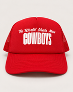A red trucker hat with white text reading 'The World Needs More COWBOYS' on the front, shown against a light gray background.